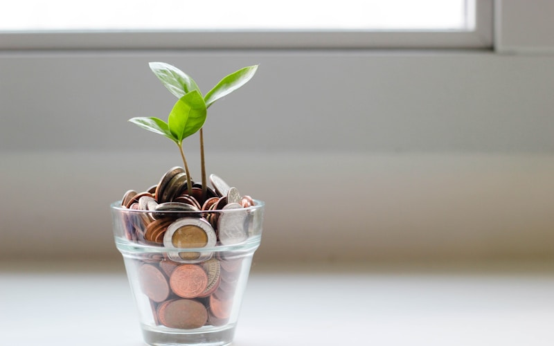 Savings jar filled with coins next to a notebook